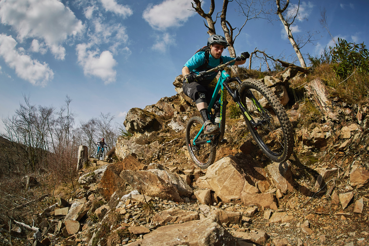 Mountain biker on rocky descent through Welsh forest