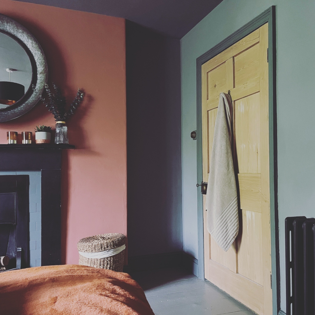 Coral wall with round mirror and fireplace mantel