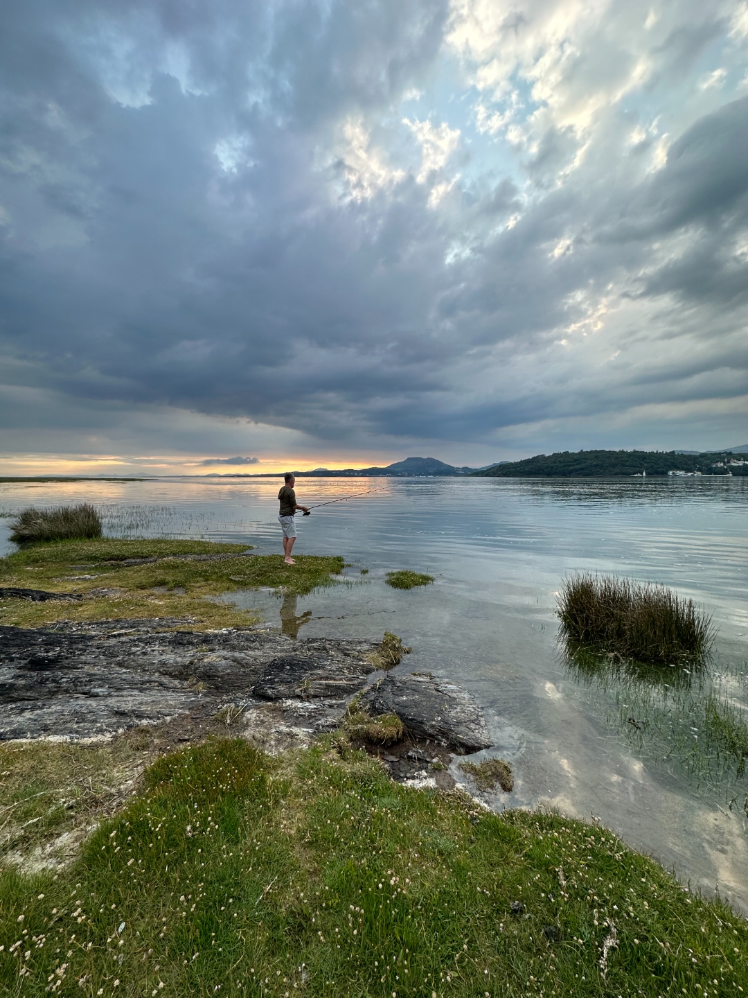 Fishing on the estuary shore under dramatic clouds