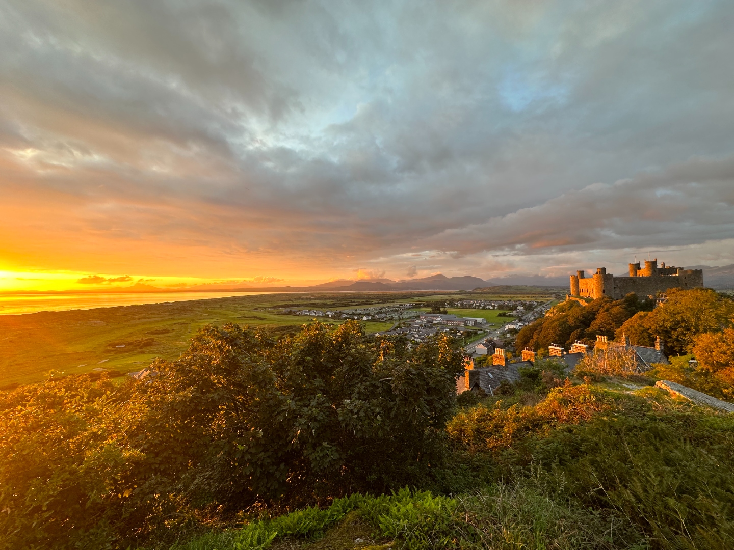 Harlech Castle and coast bathed in golden hour light