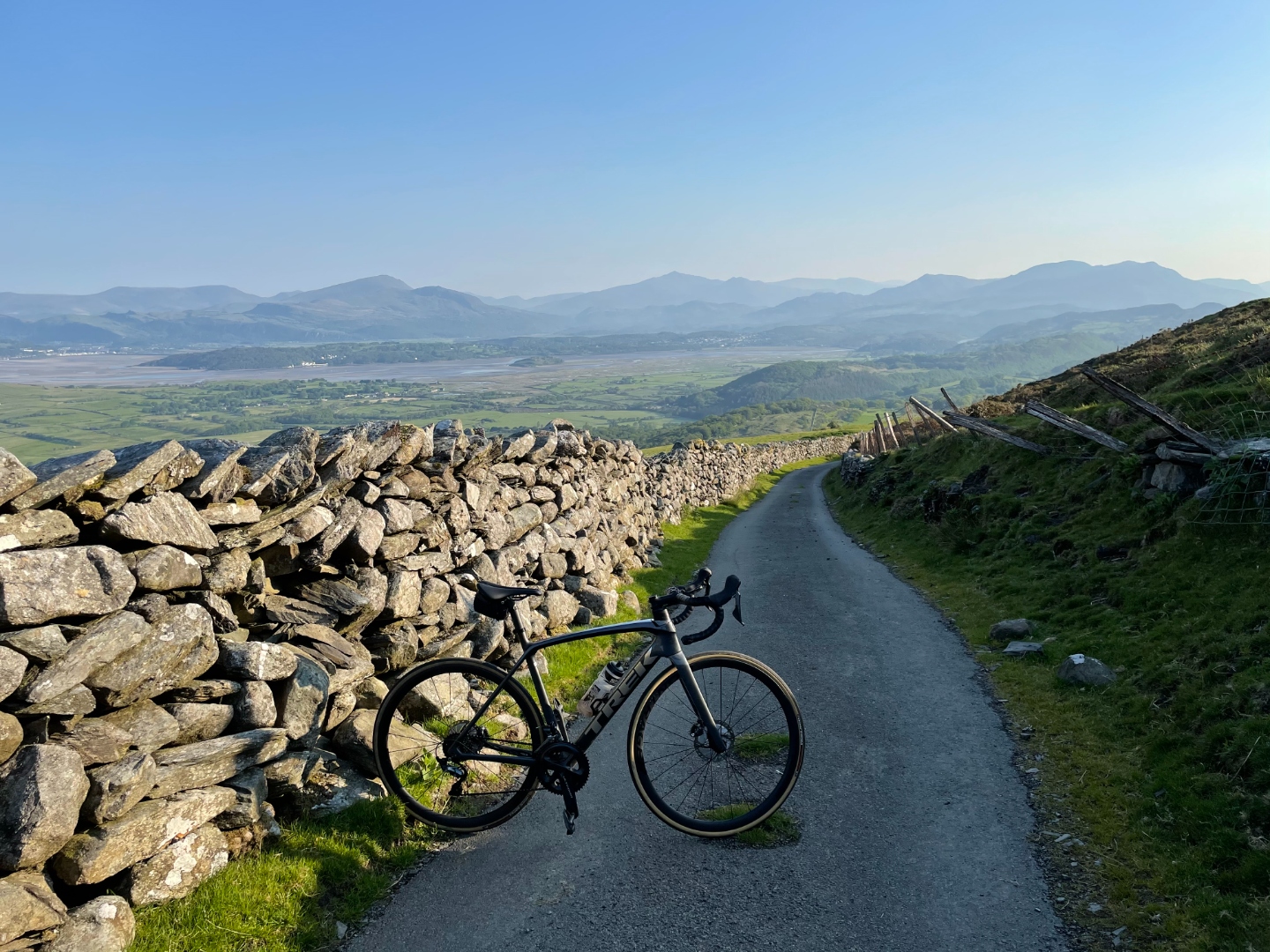 Cycling lane with dry stone wall, estuary and mountains beyond