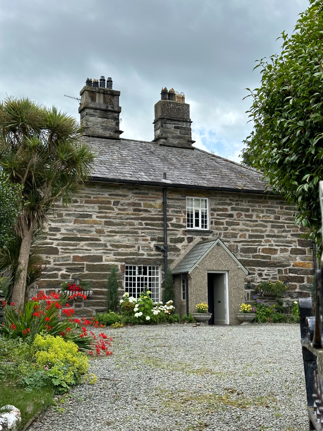 Full front view of Tyddyn Eglwys rectory with flower gardens and gravel drive