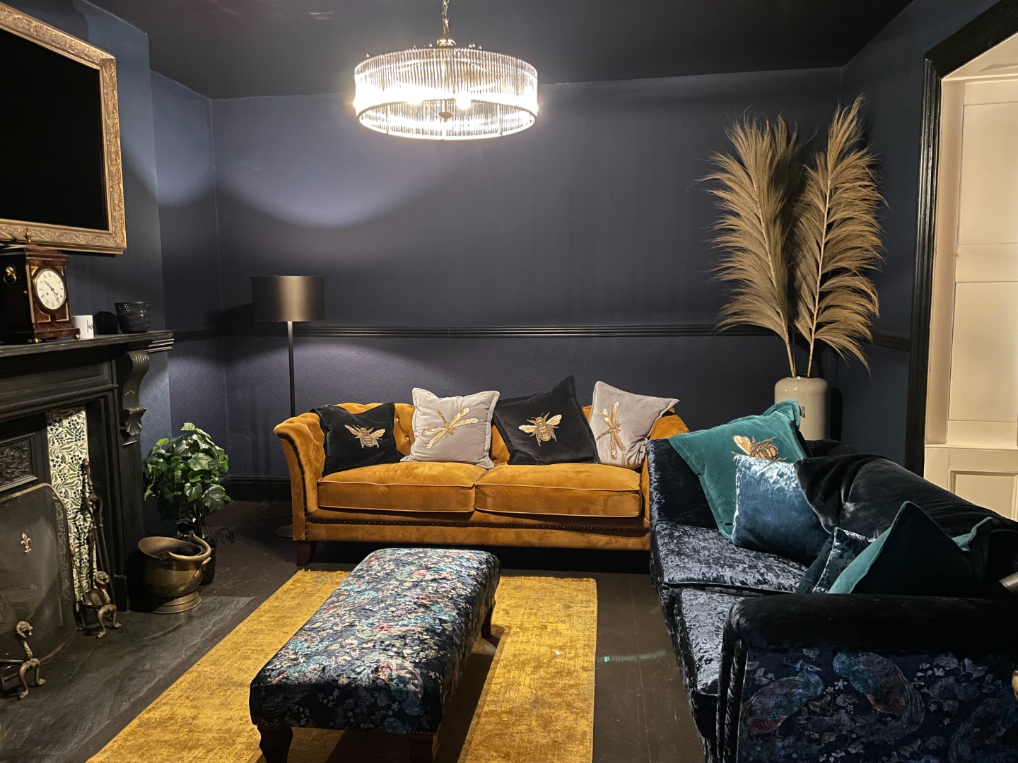 Dark-walled living room with gold Chesterfield sofa and chandelier