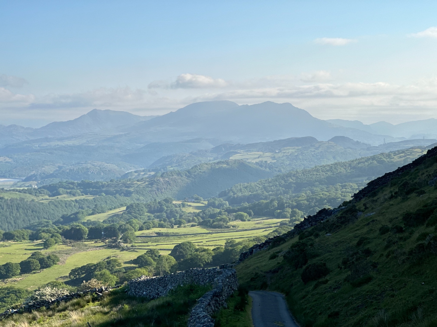 Rolling green hills with misty mountains beyond