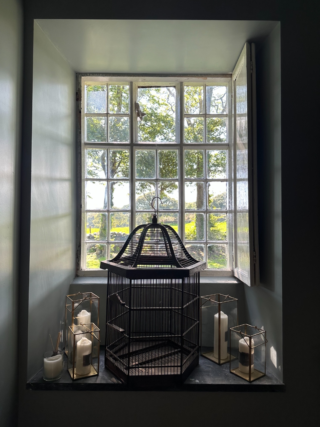 Deep windowsill with decorative birdcage and lanterns